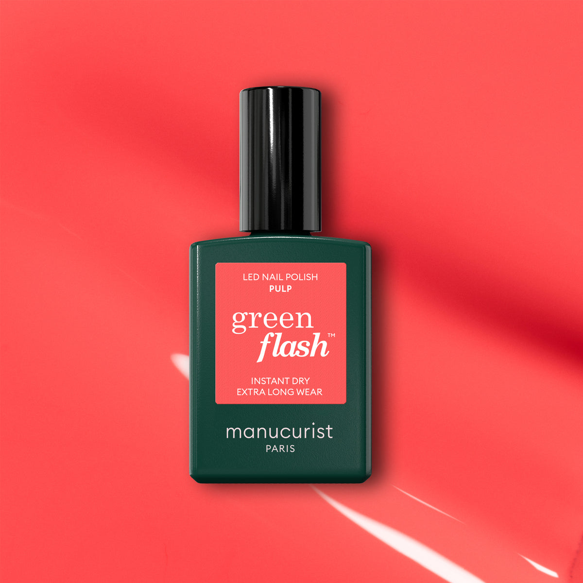 A green Manucurist Pulp Green Flash LED nail polish bottle rests on a vivid coral background, casting a soft shadow. The label features "Pulp," highlighting instant dry and extra-long wear—perfect for fans of coral pink gel polish.
