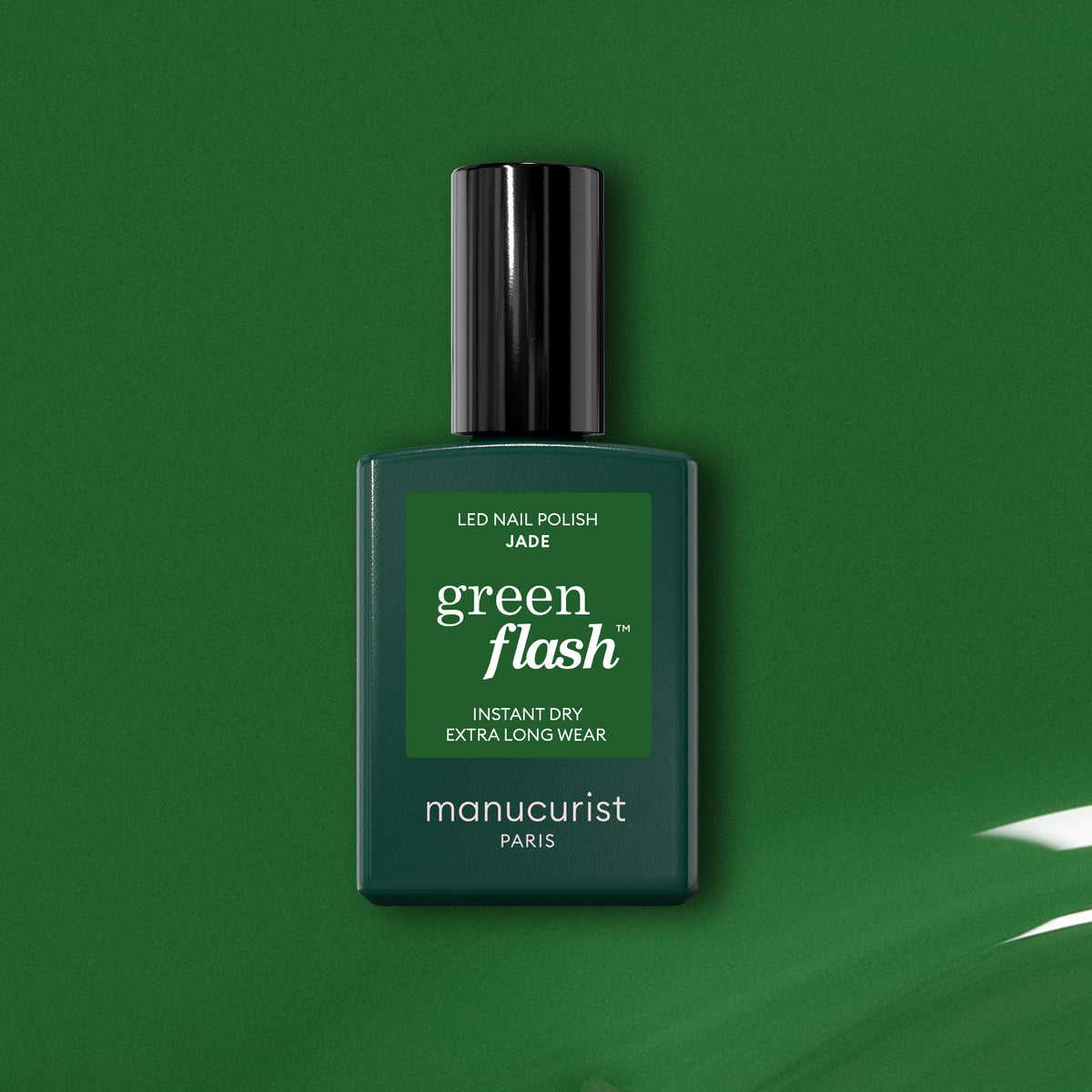 A bottle of Manucurist Jade LED gel polish stands upright on a glossy green surface with a matching mineral green background, highlighting its instant dry and extra long wear features.
