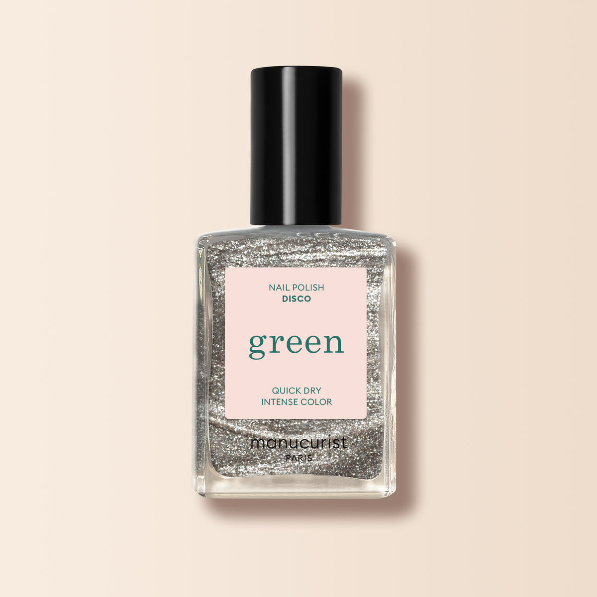 A bottle of Manucurist Disco nail polish with a black cap, filled with opaque glittery silver polish from the Green™ range. The label says Nail Polish Disco, Green, Quick Dry Intense Color on a pale pink background.