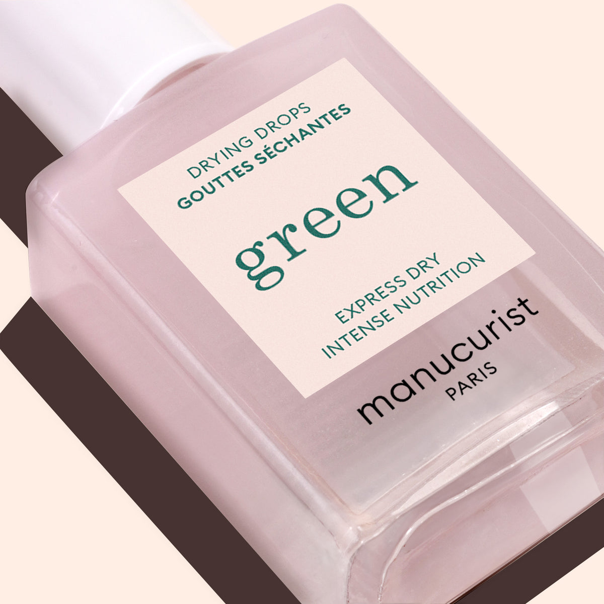 Close-up of a clear pink-tinted Manucurist Drying Drops bottle, labeled for quick express drying and nourishing nail care.