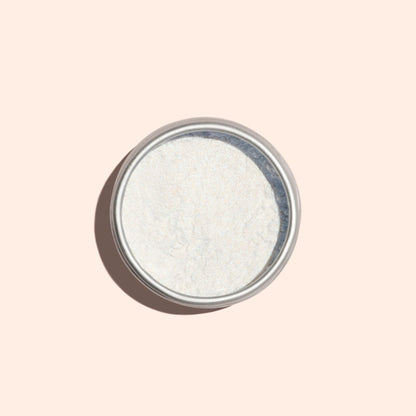 A round metal tin of Manucurist Blue Glazed Powder, a fine white manicure powder with a subtle pearly blue shimmer, is photographed from above on a light beige background.