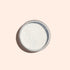 A round metal tin of Manucurist Blue Glazed Powder, a fine white manicure powder with a subtle pearly blue shimmer, is photographed from above on a light beige background.