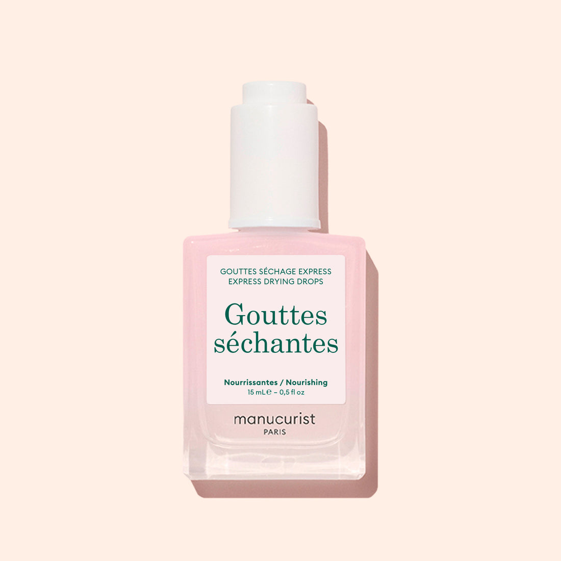 A bottle of Manucurist Drying Drops, ideal for speeding up your manicure, with a pale pink liquid, white cap, and green text on a white label shown against a light beige background.