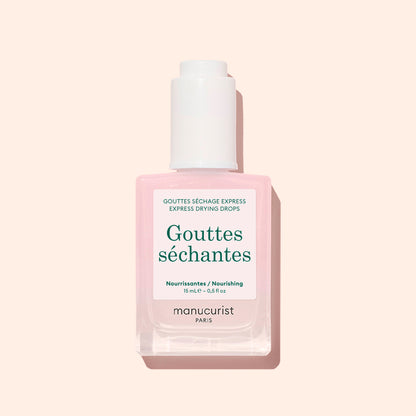 A bottle of Manucurist Drying Drops, ideal for speeding up your manicure, with a pale pink liquid, white cap, and green text on a white label shown against a light beige background.