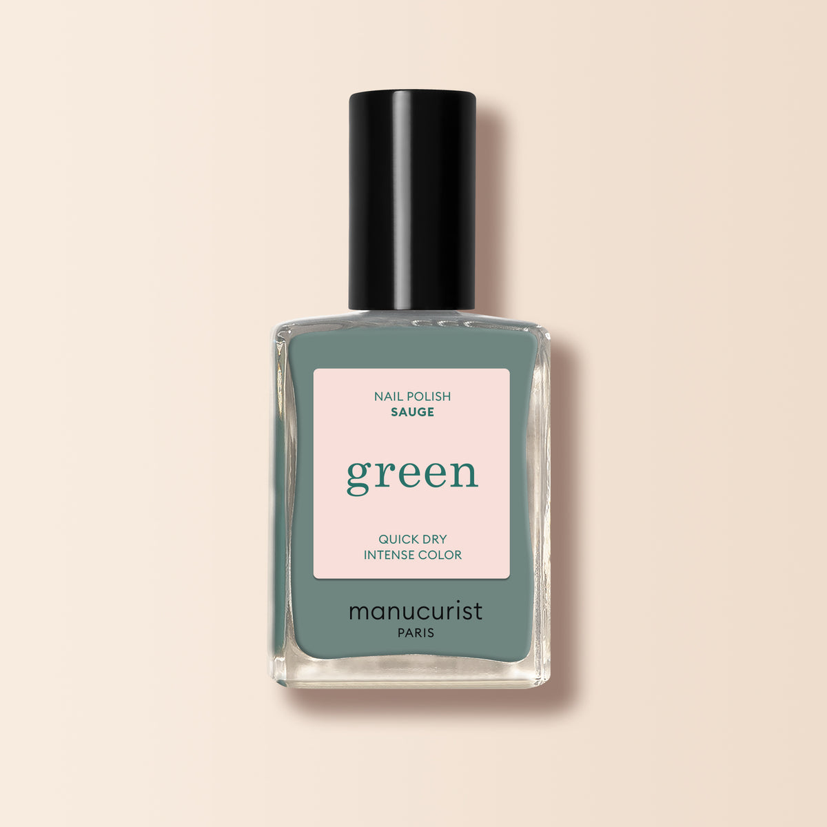 A bottle of Manucurist Sage nail polish from the Green™ range, featuring a muted green shade called Sage, quick dry intense color, and a black cap, displayed on a light beige background.