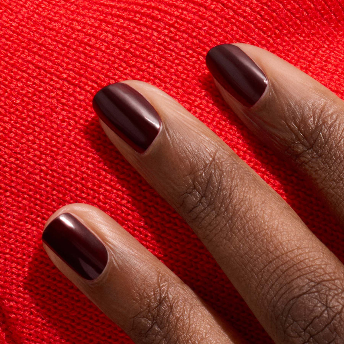 Three fingers with short, neatly manicured nails painted in Manucurist&