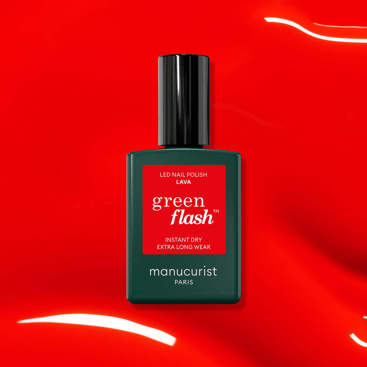 A bottle of Manucurist-test Lava - Free is displayed on a glossy, vibrant red surface with reflective light streaks, highlighting it as the perfect summer nail color.