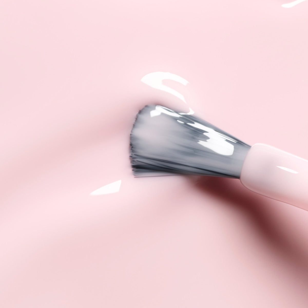 A Manucurist makeup brush with white bristles spreads Milky Pink nail polish on a smooth, glossy pink surface.