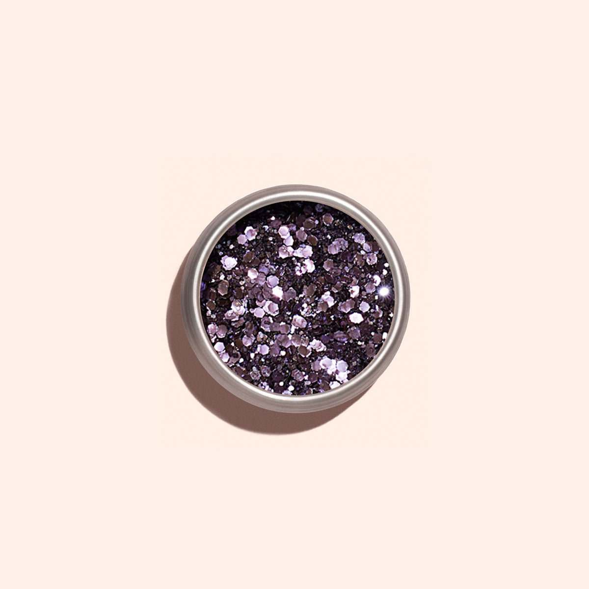 Manucurist’s Lilac biodegradable glitter is a small, round pot of chunky metallic purple plant-based glitter on a light beige surface—perfect for eco-friendly nail art fans.