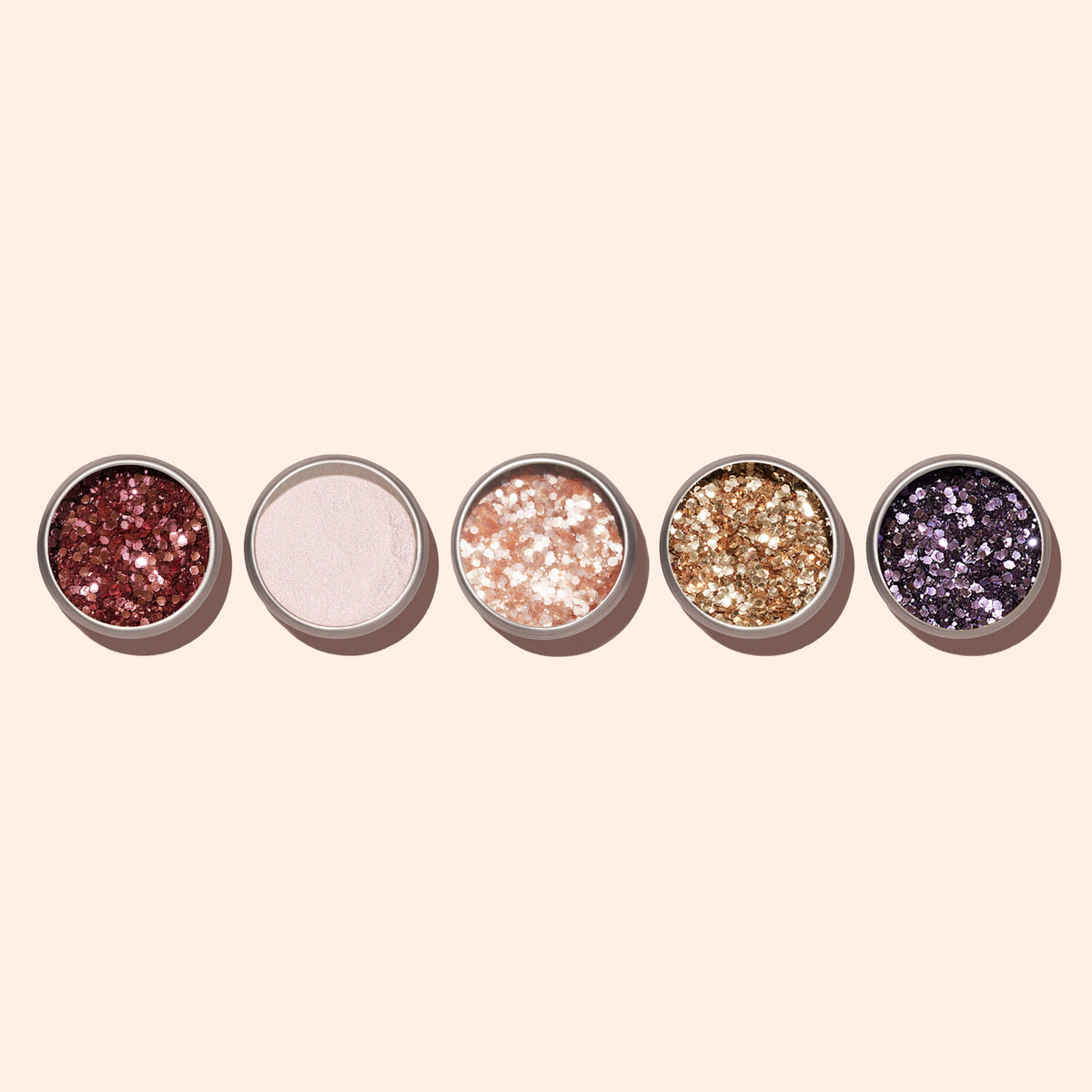 Five round eyeshadow pans are lined up on a light beige background, showcasing Manucurist&