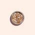 A round container of Manucurist Rose Gold biodegradable glitter, perfect for nail art, sits on a light beige background with a soft shadow to the left.