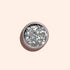 A round container of Manucurist Silver biodegradable glitter, shown from above on a pale beige background—ideal for dazzling nail art designs.