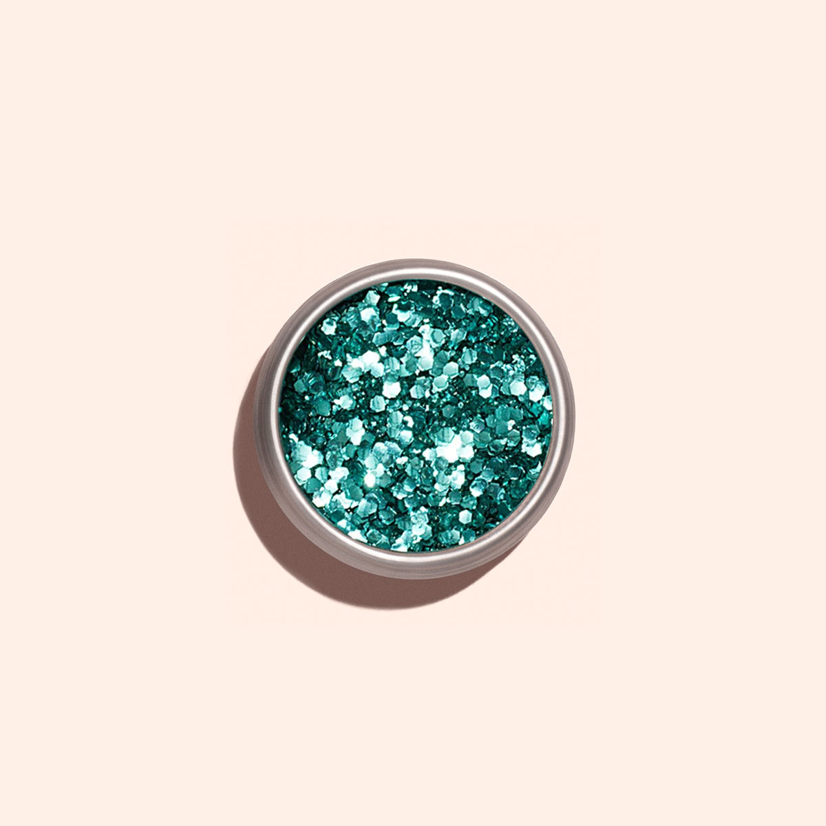 A small round container of Manucurist Turquoise biodegradable glitter viewed from above against a light beige background—ideal for adding an eco-friendly sparkle to your nail art.