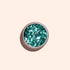 A small round container of Manucurist Turquoise biodegradable glitter viewed from above against a light beige background—ideal for adding an eco-friendly sparkle to your nail art.