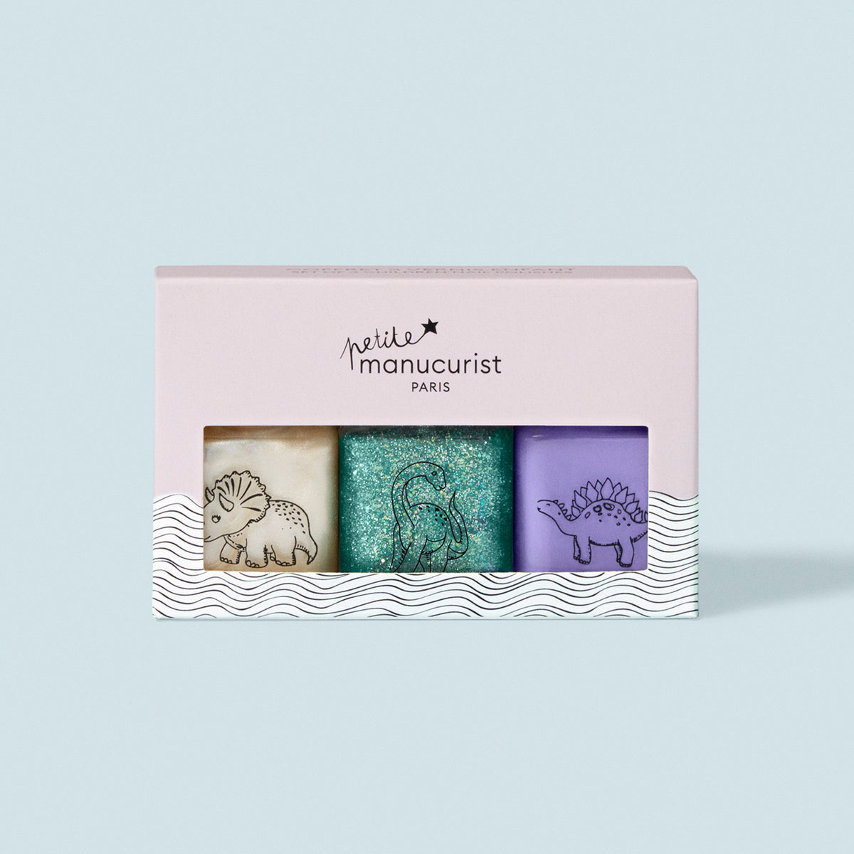 The Wild Life Collection by Manucurist is a kids nail polish set with three washable bottles: beige with triceratops, green glitter with brontosaurus, and purple stegosaurus—each featuring fun dinosaur art.