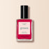A bottle of Manucurist-test nail polish in the pink shade Peonie OLD, featuring a black cap, is photographed against a light beige background.