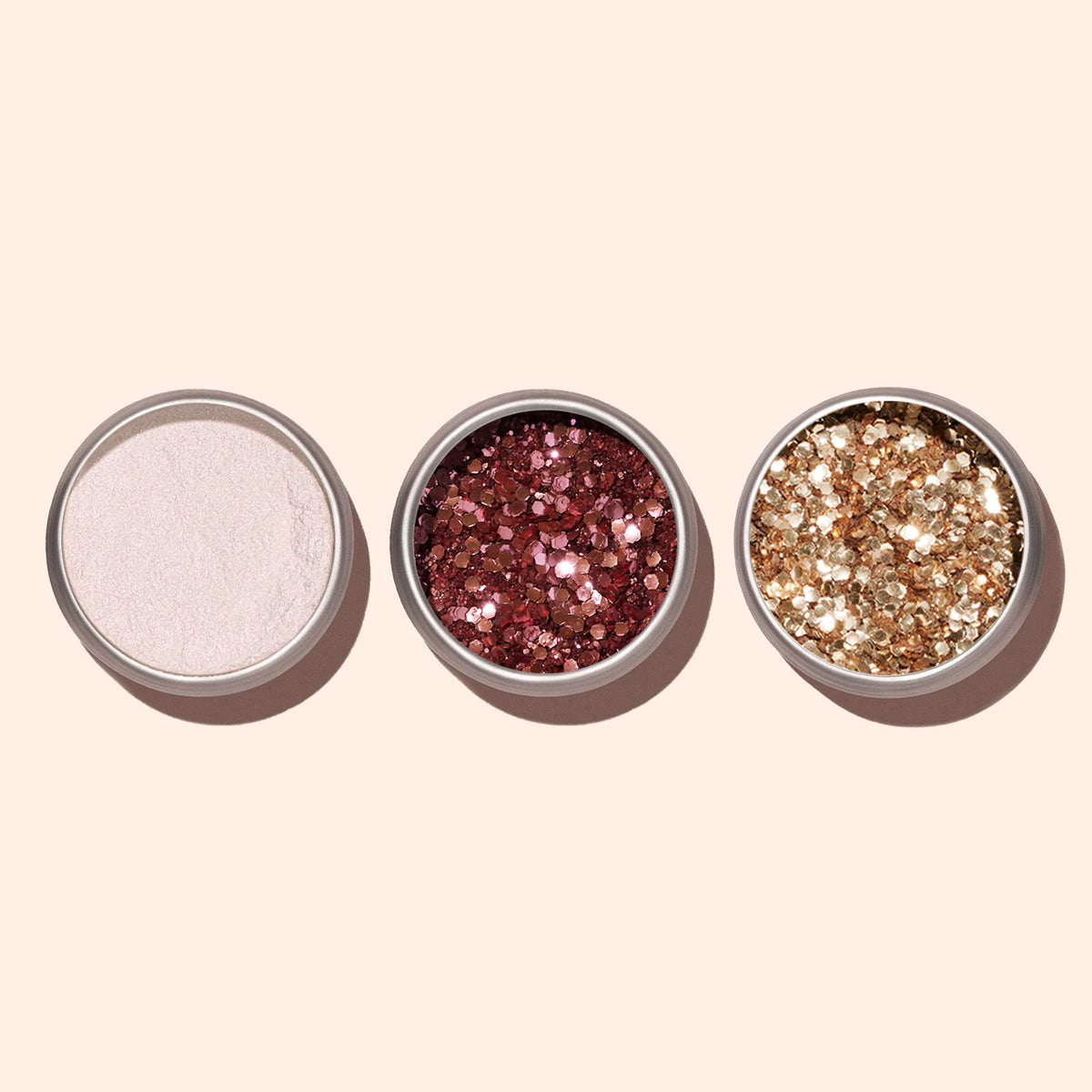 Three round containers from Manucurist are shown on a light beige background: one with pale pink powder, one with gold glitter, and one with Rose Gold biodegradable glitter perfect for nail art.