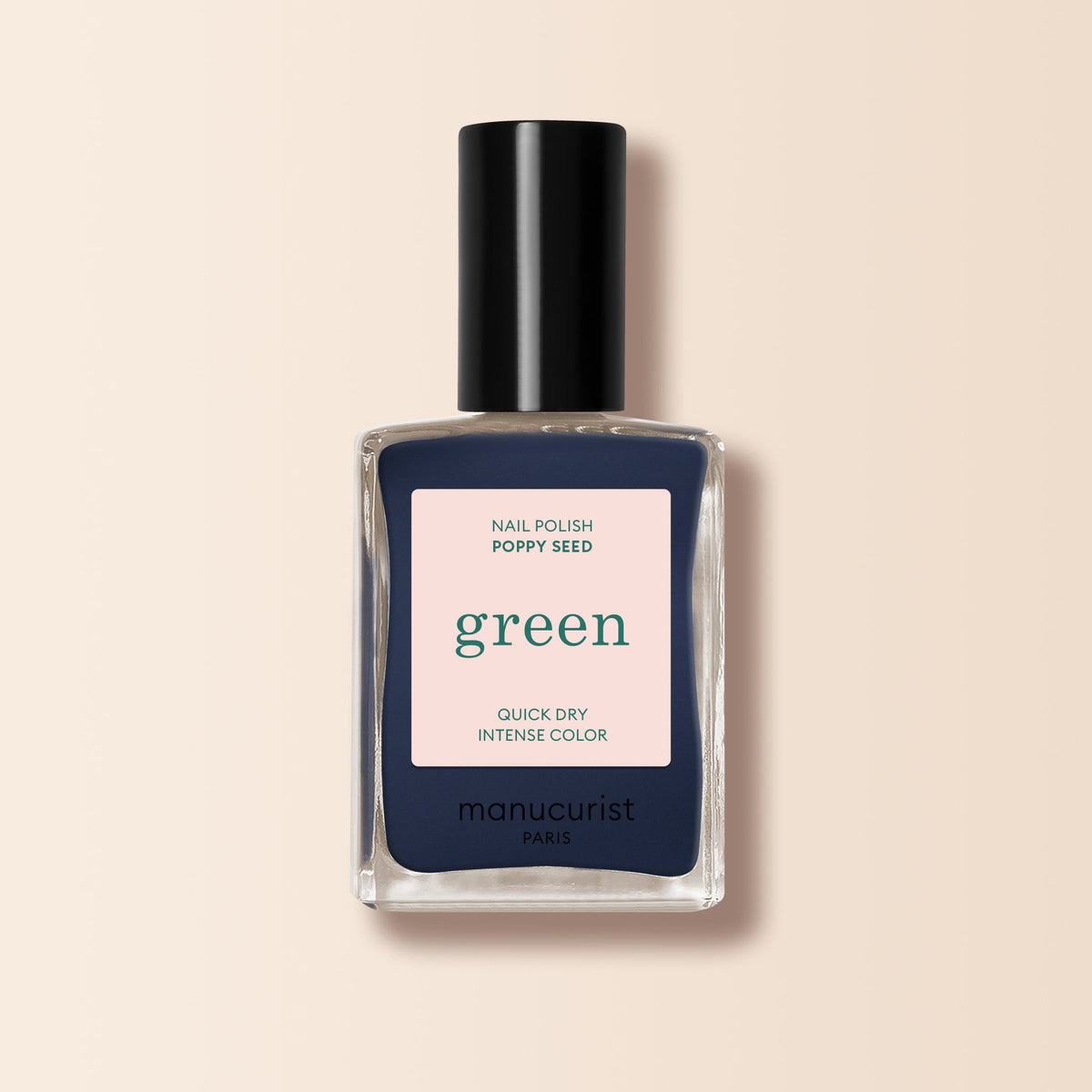 A bottle of Manucurist nail polish in the shade Poppy Seed, a chic greyish blue, is displayed in a square glass bottle with a black cap and beige label against a light beige background.