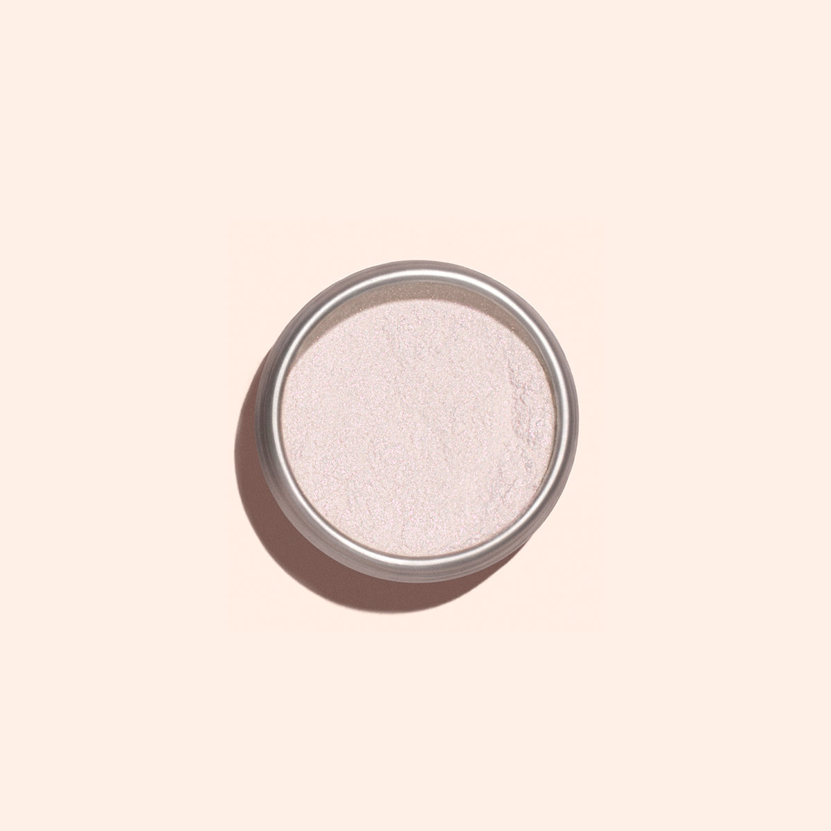 A round tin of Manucurist Pink Glazed Effect Powder displays its delicate pearlescent sheen, photographed against a pale peach background.