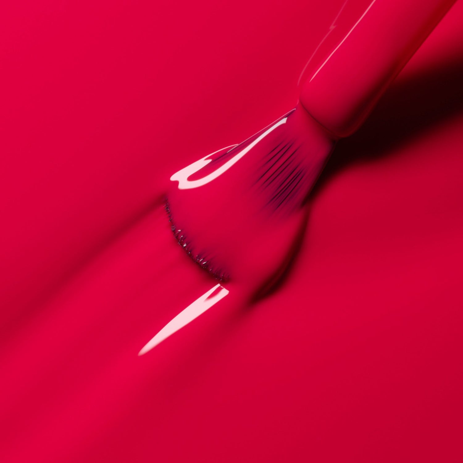 A close-up of a brush spreading Manucurist-test Peonie OLD bright pink vegan nail polish, creating smooth, glossy strokes on a matching pink surface.