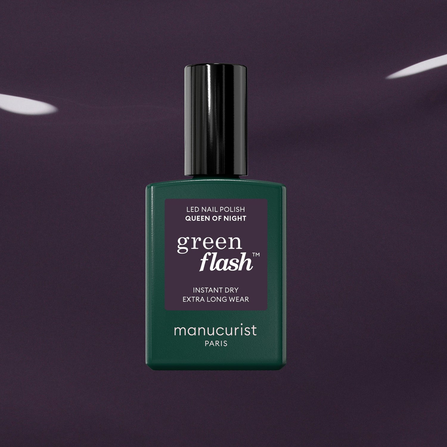 A bottle of Manucurist Queen of Night gel nail polish stands against a dark, glossy backdrop. The bottle features a deep green shade, black cap, and crisp white text on the label.