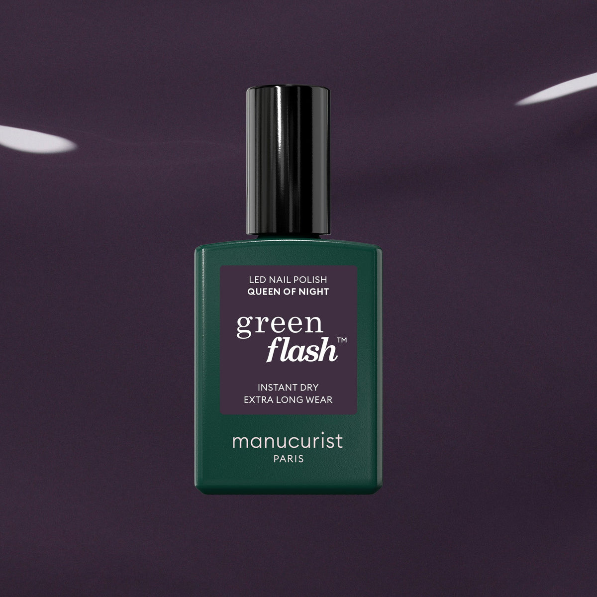 A bottle of Manucurist Queen of Night gel nail polish stands against a dark, glossy backdrop. The bottle features a deep green shade, black cap, and crisp white text on the label.