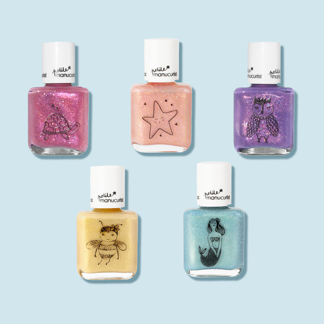 Five bottles of Manucurist’s Customisable Rainbow Petite Manucurist kids nail polishes in pink, peach, purple, yellow, and blue with cute black turtle, starfish, owl, bee, and mermaid illustrations on a light blue background.