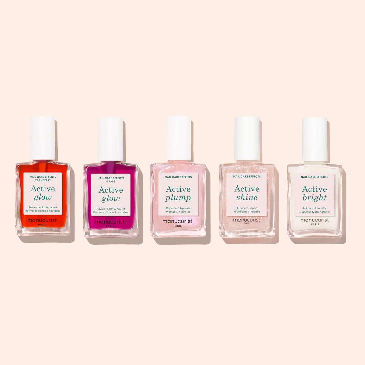 Five bottles of Manucurist nail care polish, including Active™ Glow Cranberry, Active Plump, Active Shine, and Active Bright, are aligned in a row on a light pink background. Each bottle features a nourishing plant-based formula that promotes healthy nails and delivers vibrant color—such as the stunning cranberry gloss of Active™ Glow Cranberry, perfect for any occasion.
