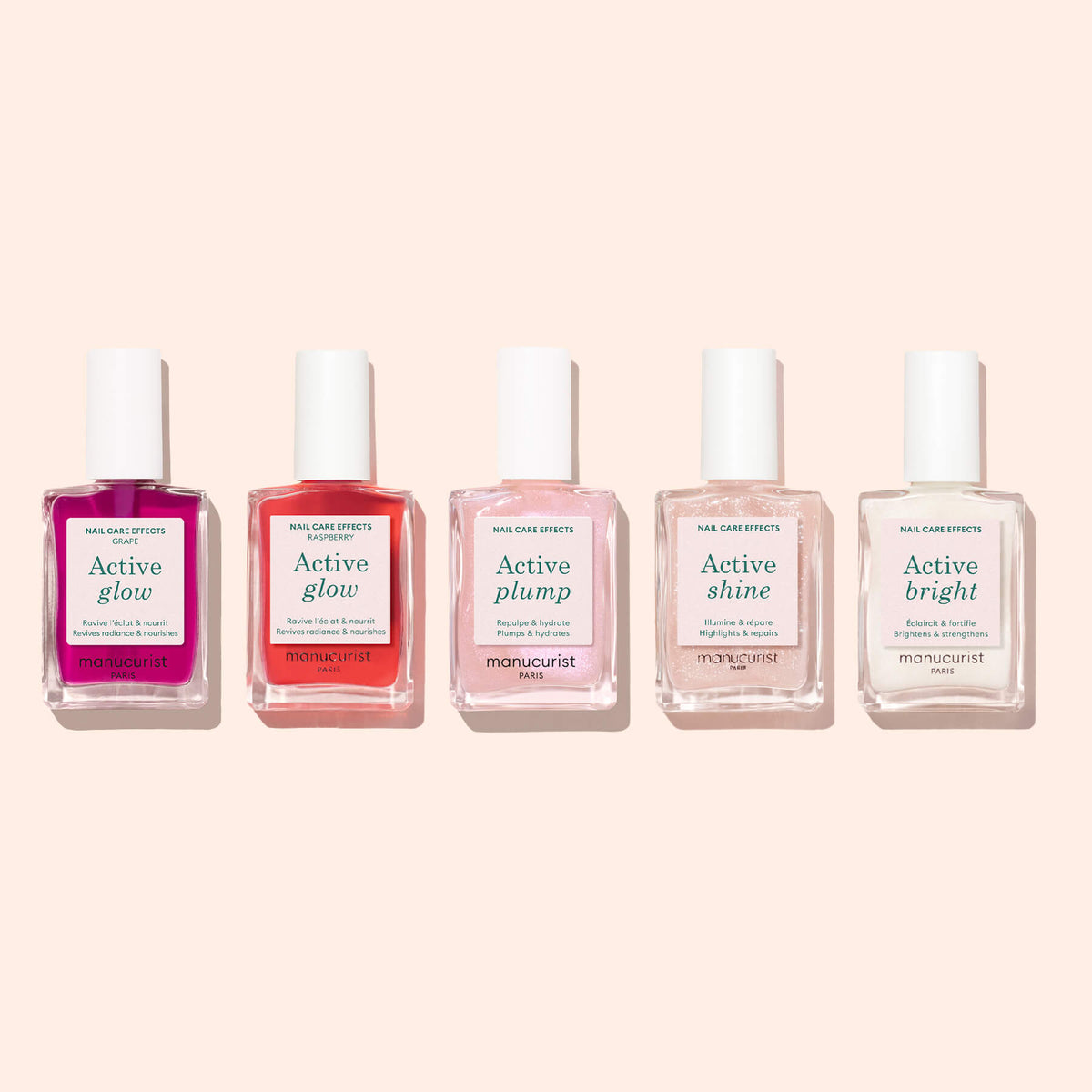 Five bottles of Manucurist nail care products are arranged in a row, each showcasing a unique color and label: including Active™ Glow Grape alongside other shades like Active Plump, Active Shine, and Active Bright. Presented in soft tones such as lilac nail polish, they rest on a pale pink background for a naturally radiant look.