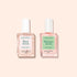 Two square glass bottles with white caps contain pink nail care liquids from Manucurist’s Basic Routine - Damaged Nails set, designed to repair and strengthen brittle nails. The left bottle is labeled Base S.O.S., and the right is labeled Masque S.O.S. Both products are by Manucurist, shown on a light beige background.