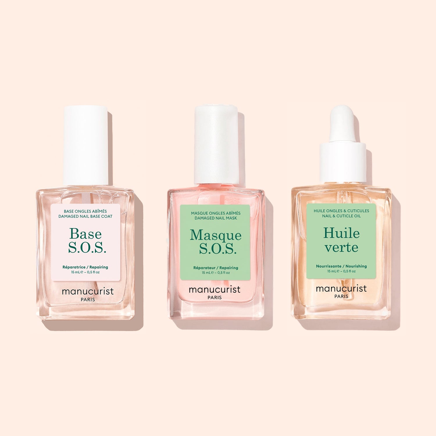 Three glass bottles from the Manucurist Basic Routine - Damaged Nails set—Base S.O.S., Masque S.O.S., and Huile verte—are arranged side by side on a light beige background, each specially formulated to strengthen brittle nails and support your nail care routine.