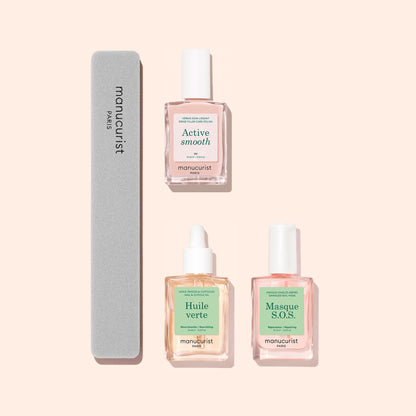 Three bottles from Manucurist’s Basic Routine - Ridged Nails set and a gray nail file are arranged on a pale pink background. The bottles in the set—Active Smooth, Huile Verte, and Masque S.O.S.—are each formulated to address issues like ridged nails and provide nourishing cuticle care for healthier-looking hands.