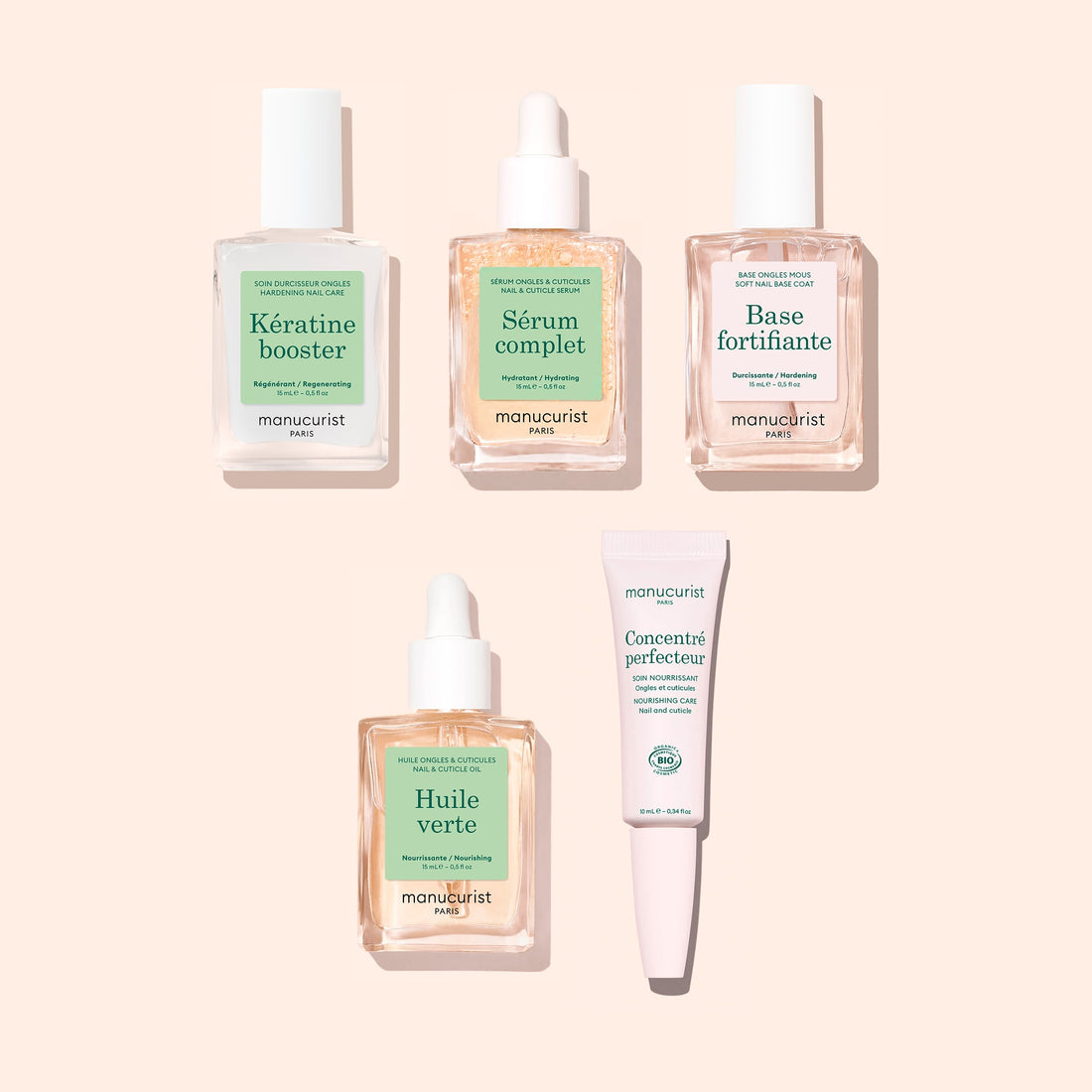 Five nail care products from Manucurist’s Basic Routine – Soft Nails collection—each in square glass bottles with green and white labels, featuring droppers and a tube—are neatly arranged on a pale peach background. These essentials are perfect for elevating your nail care routine or applying a nourishing serum designed to help strengthen soft nails.