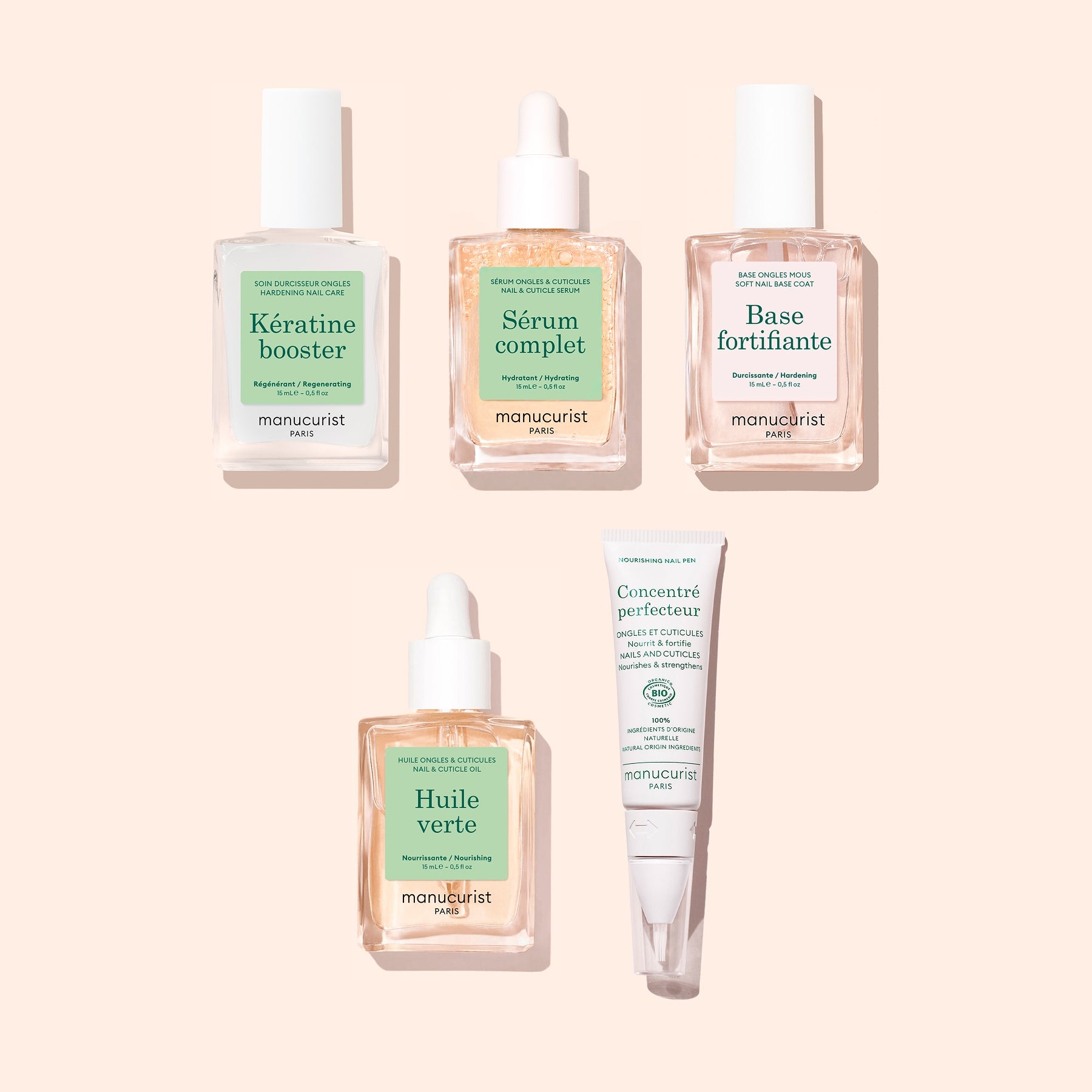 Five nail care products from Manucurist’s Basic Routine – Soft Nails collection—each in square glass bottles with green and white labels, featuring droppers and a tube—are neatly arranged on a pale peach background. These essentials are perfect for elevating your nail care routine or applying a nourishing serum designed to help strengthen soft nails.