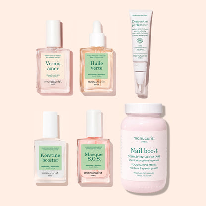Six manicure products from Manucurist’s Ultimate Routine - Bitten Nails set—including a nail polish, green oil, perfecting concentrate, keratin booster, SOS mask, and a powder supplement for nail strengthening and overall care—are arranged neatly on a light beige background.