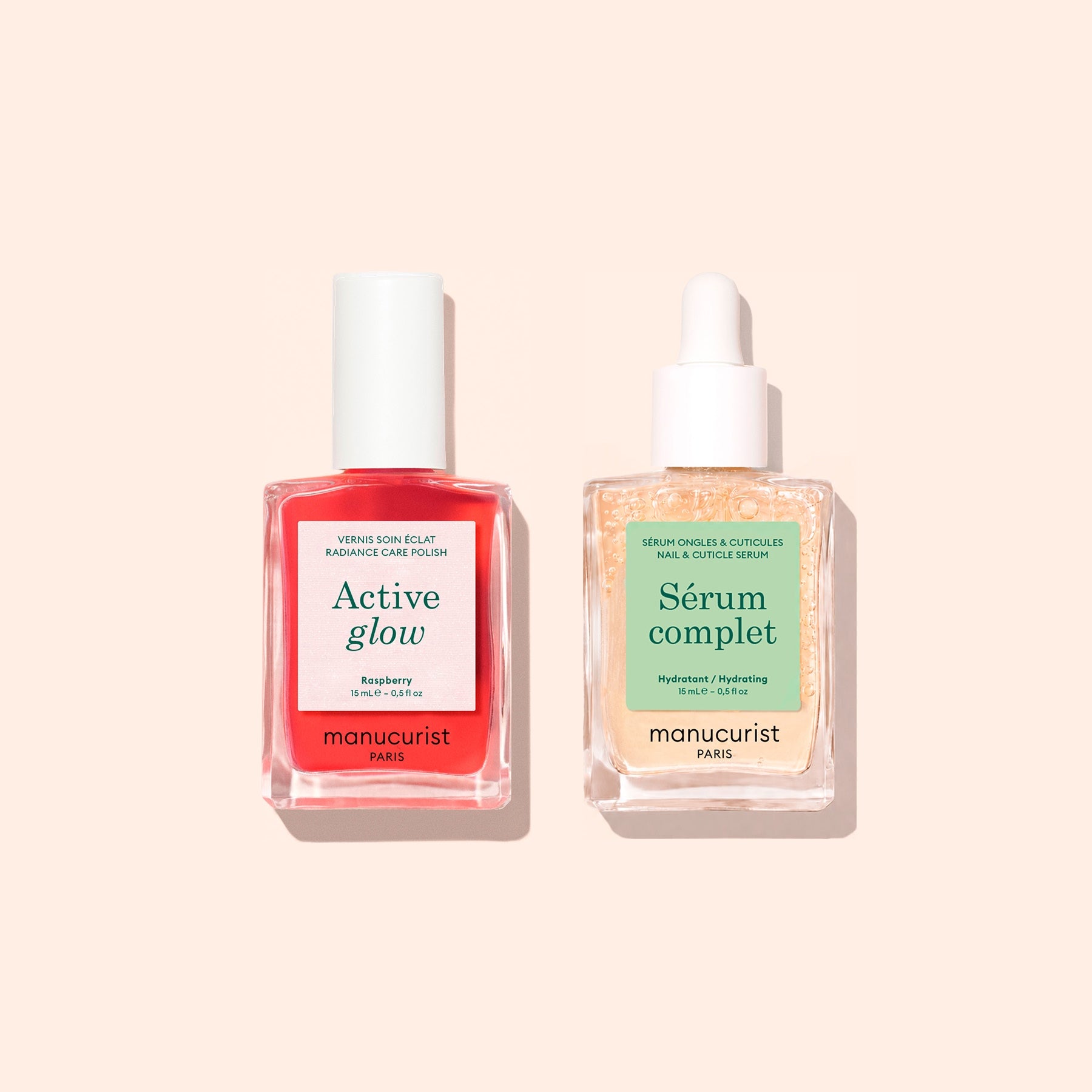 Two Manucurist manicure essentials from the “Basic Routine - Sensitive Nails” set are neatly arranged side by side on a beige background: a pink bottle labeled “Active Glow” with a white cap—perfect for hydrating polish—and a clear dropper bottle labeled “Sérum Complet,” an essential cuticle serum. Both feature the signature Manucurist branding.