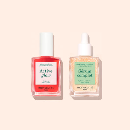 Two Manucurist manicure essentials from the “Basic Routine - Sensitive Nails” set are neatly arranged side by side on a beige background: a pink bottle labeled “Active Glow” with a white cap—perfect for hydrating polish—and a clear dropper bottle labeled “Sérum Complet,” an essential cuticle serum. Both feature the signature Manucurist branding.