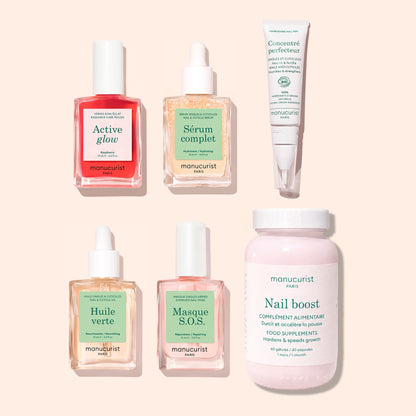 Five bottles of Manucurist Ultimate Routine - Sensitive Nails serums and a tube, alongside a pink bottle labeled Nail Boost Food Supplements, are arranged on a light beige background. Each Manucurist product features a pastel label with a dropper or cap, designed to nourish and strengthen nails as part of an effective nail care treatment for healthier, more resilient nails.