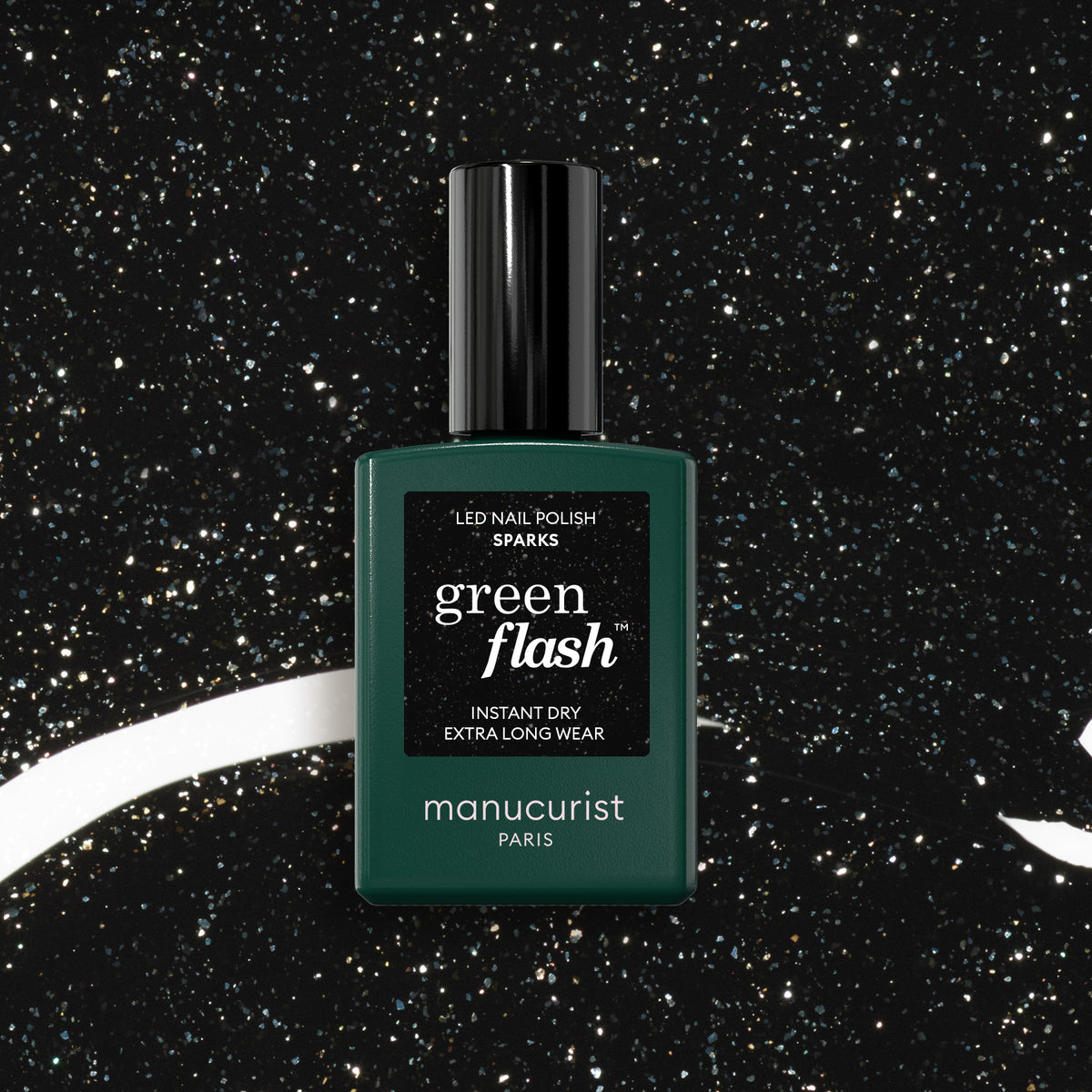 A bottle of Sparks LED gel polish by Manucurist sits against a black, glittery background with white swirls, evoking a starry night sky. The bottle features a dark green hue, black cap, and sharp white text.