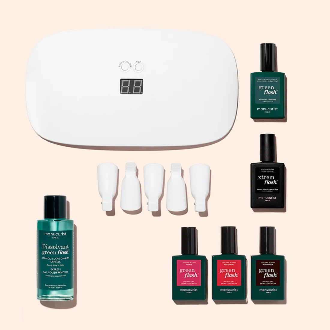 Introducing the Manucurist Starter Kit: a complete gel polish set that includes a white LED lamp, nail polish remover, four bottles of Green Flash nail polish, a vitaminized base coat for healthy nails, one Black X-Trem Flash bottle, and four white nail clips—all beautifully arranged on a light pink background. Perfect for achieving a long-lasting manicure at home.