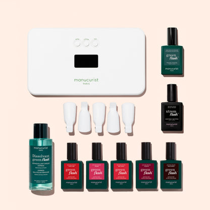 The Manucurist Super Starter Kit includes a nail lamp, four nail polish bottles, a vitaminized base coat, one remover bottle, four white nail clips, and three black bottles—all thoughtfully arranged on a light background for an ultra-glossy manicure.