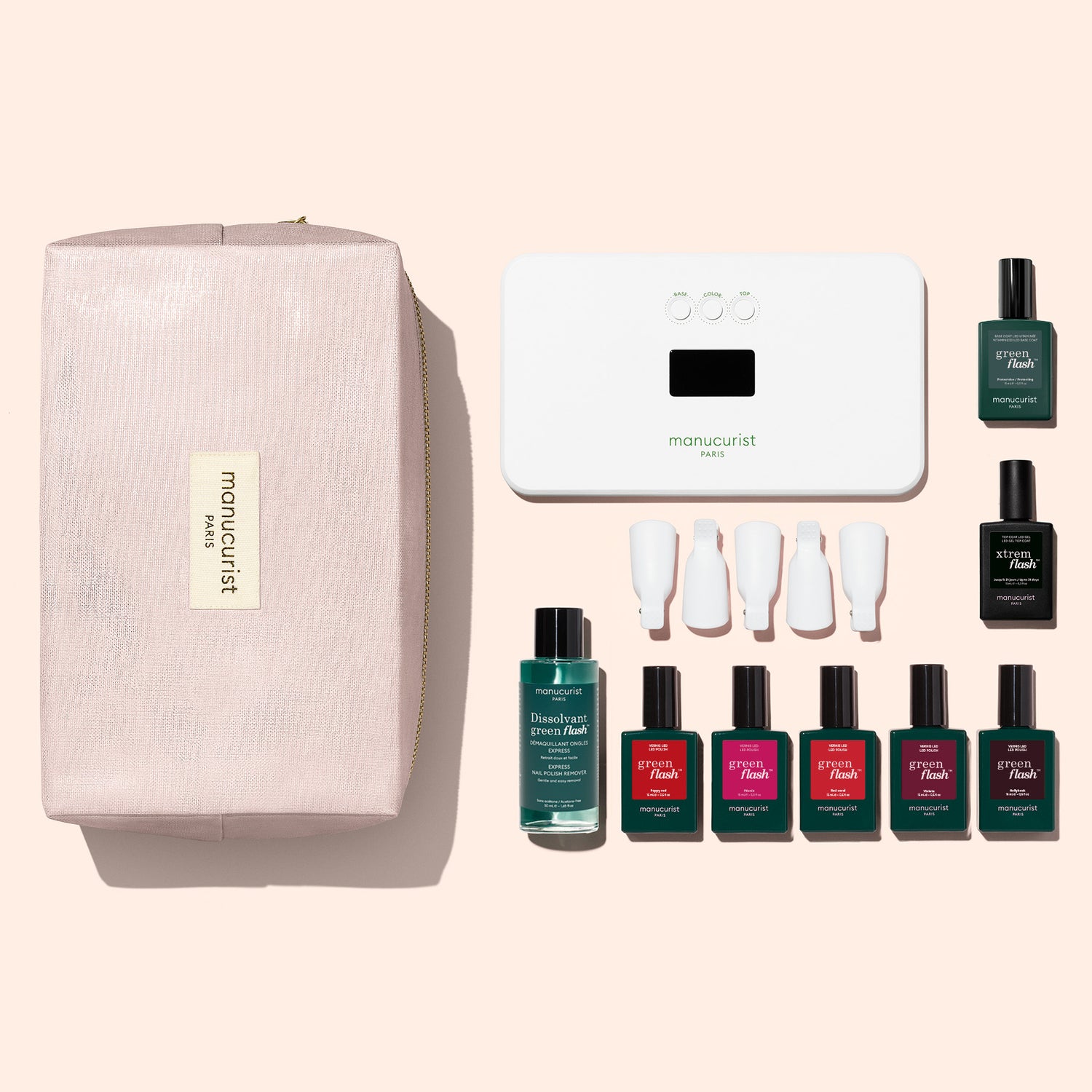 The Manucurist Super Starter Kit, featuring a pink zippered pouch, a white nail lamp, two bottles of Green Flash gel polish for an ultra-glossy manicure, a remover bottle, four white nail clips, and five bottles of colorful nail polish, is displayed on a light background.