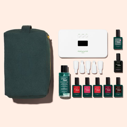 The Manucurist Super Starter Kit features a dark green pouch, a white LED nail lamp, five gel polishes in assorted colors, a Vitaminized Base Coat, and four white caps, all displayed on a light beige background.