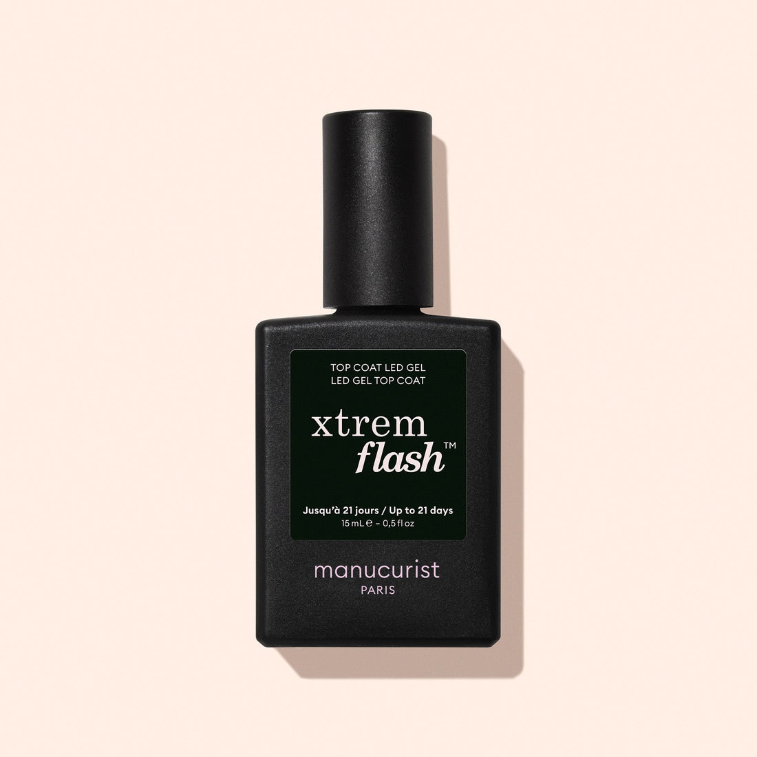 A black rectangular bottle of Manucurist Xtrem Flash™ Gel Top Coat stands upright against a pale beige background, offering a long-lasting manicure with easy, express removal.