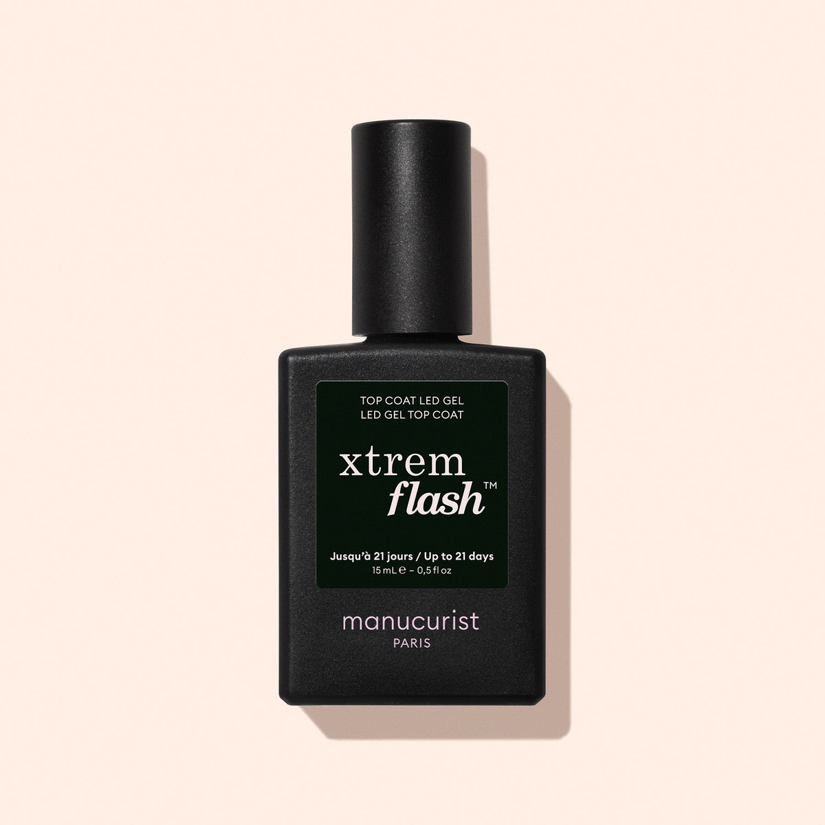 A black rectangular bottle of Manucurist Xtrem Flash™ Gel Top Coat stands upright against a pale beige background, offering a long-lasting manicure with easy, express removal.