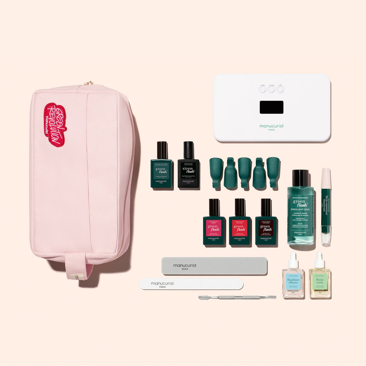 The Manucurist Addict Kit, featuring a pink zippered pouch filled with essential manicure tools—including nail polishes, files, a cuticle pusher, Vitaminized Base Coat, gel remover, and a white LED nail lamp—is neatly arranged on a pale background, offering everything you need for an ultra-glossy manicure.