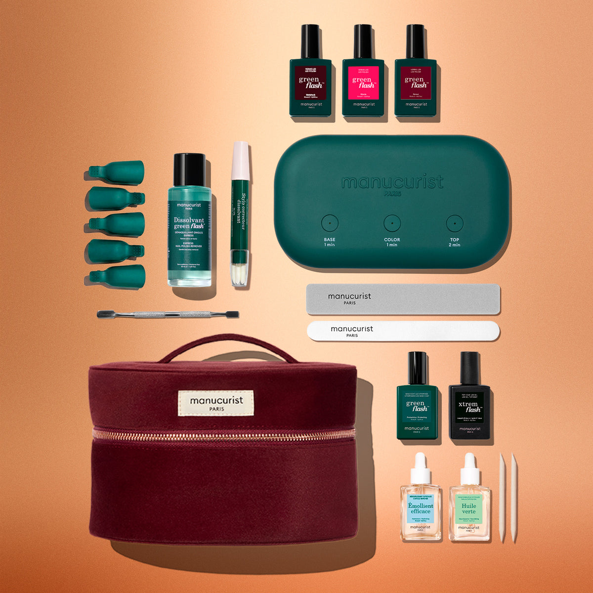 A Manucurist Green Flash™ Addict Kit in a dark red zippered travel case, featuring a portable LED lamp, three polishes, two oils, remover, finger clips, a cuticle pusher, files, and wooden sticks.