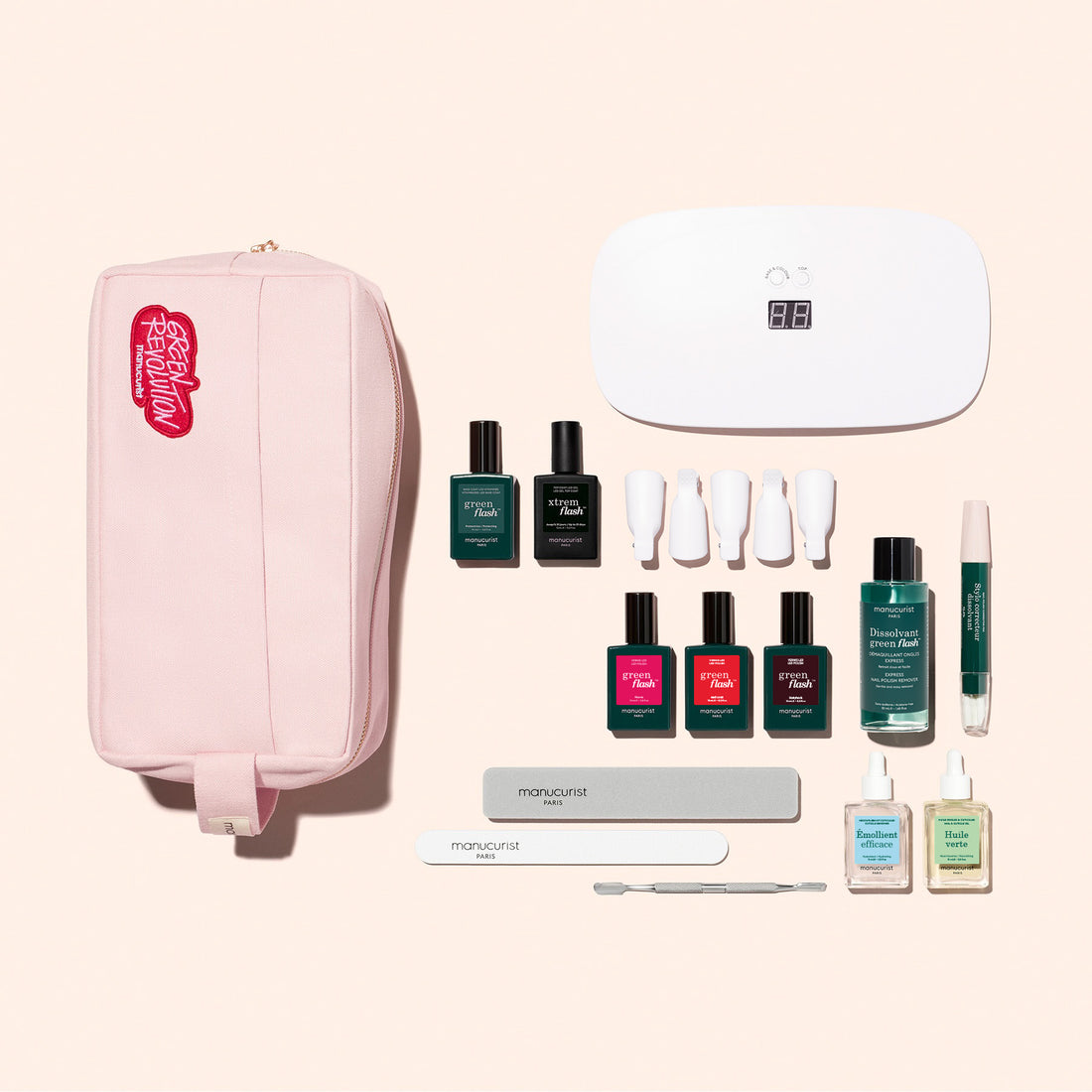 A flat lay of the Manucurist Addict Kit, featuring a pink pouch, white LED nail lamp, colorful Green Flash gel polishes, care tools, files, Vitaminized Base Coat  serums—perfectly arranged for an ultra-glossy manicure.