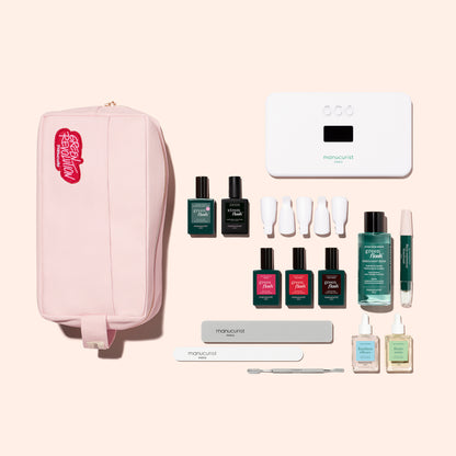 The Manucurist Addict Kit, featuring a pink manicure kit bag with a red patch, Green Flash gel polish, nail tools, and an LED lamp, contains everything needed for an ultra-glossy manicure.