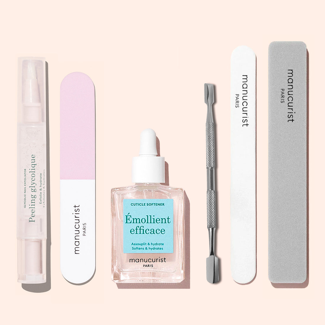 The Manucurist Glossy Booster Duo includes a nail exfoliator pen, two nail files, a cuticle softener with dropper, a cuticle pusher, and a glossy nail file, all arranged on a light background.